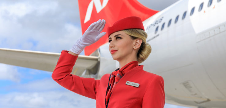 a woman in red uniform saluting with a plane in the background