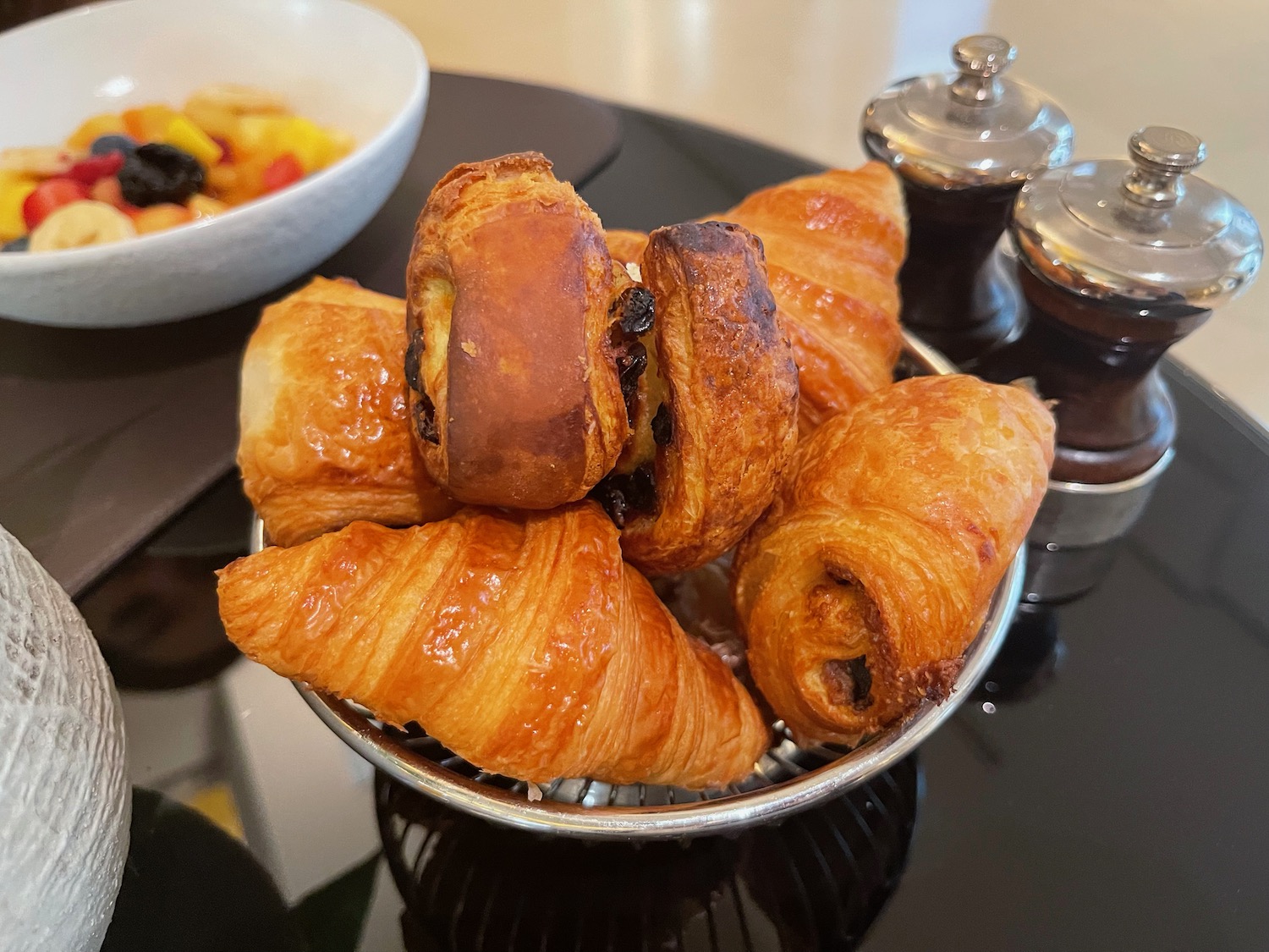 a basket of pastries and a bowl of fruit