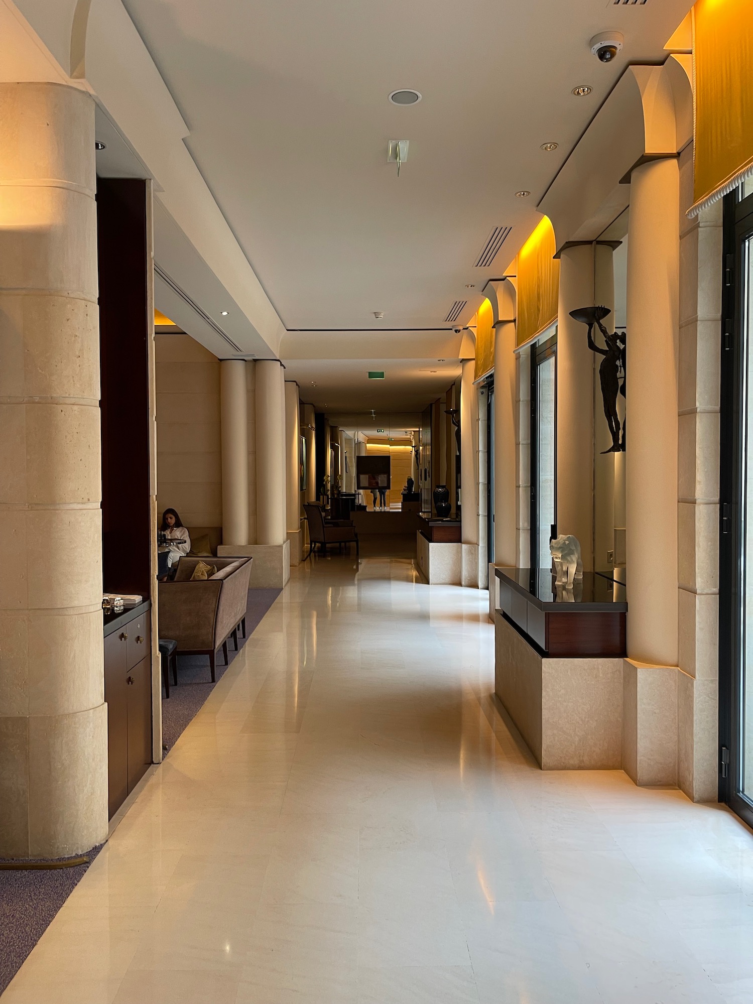 a hallway with columns and a woman sitting on a couch