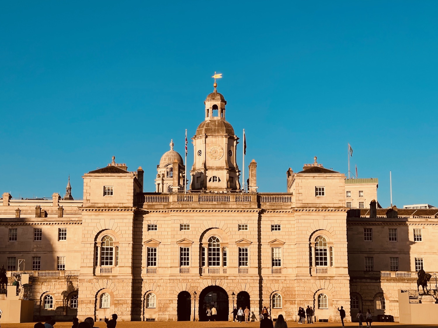 a large stone building with a dome and people walking in front