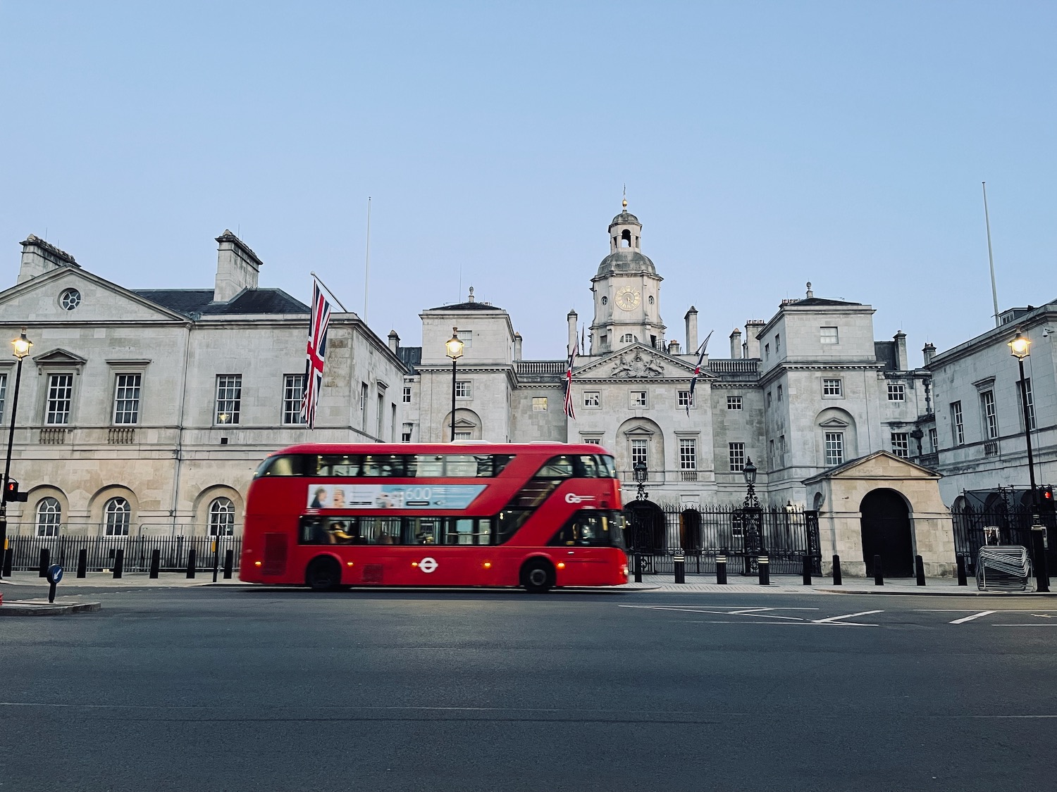 a red double decker bus in front of Horse Guards