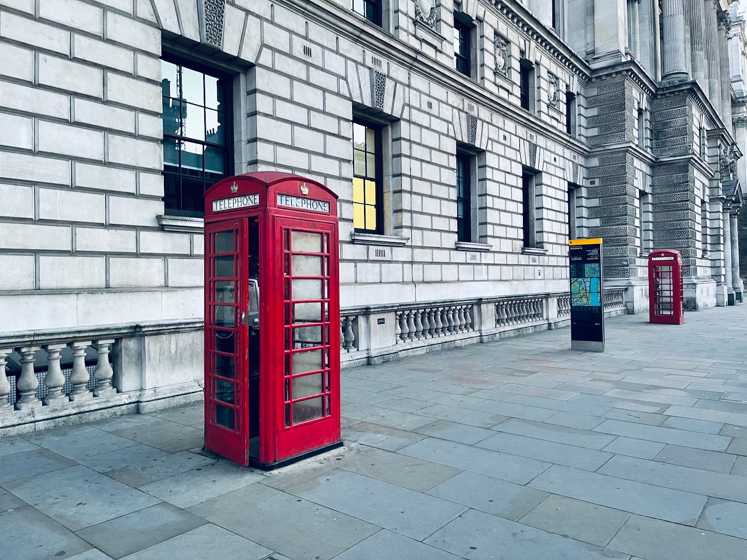 a red telephone booth in front of a stone building