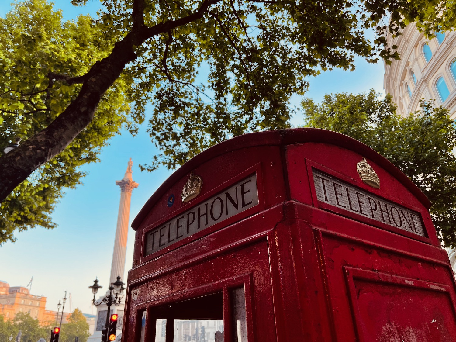 a red telephone booth with a tall monument in the background