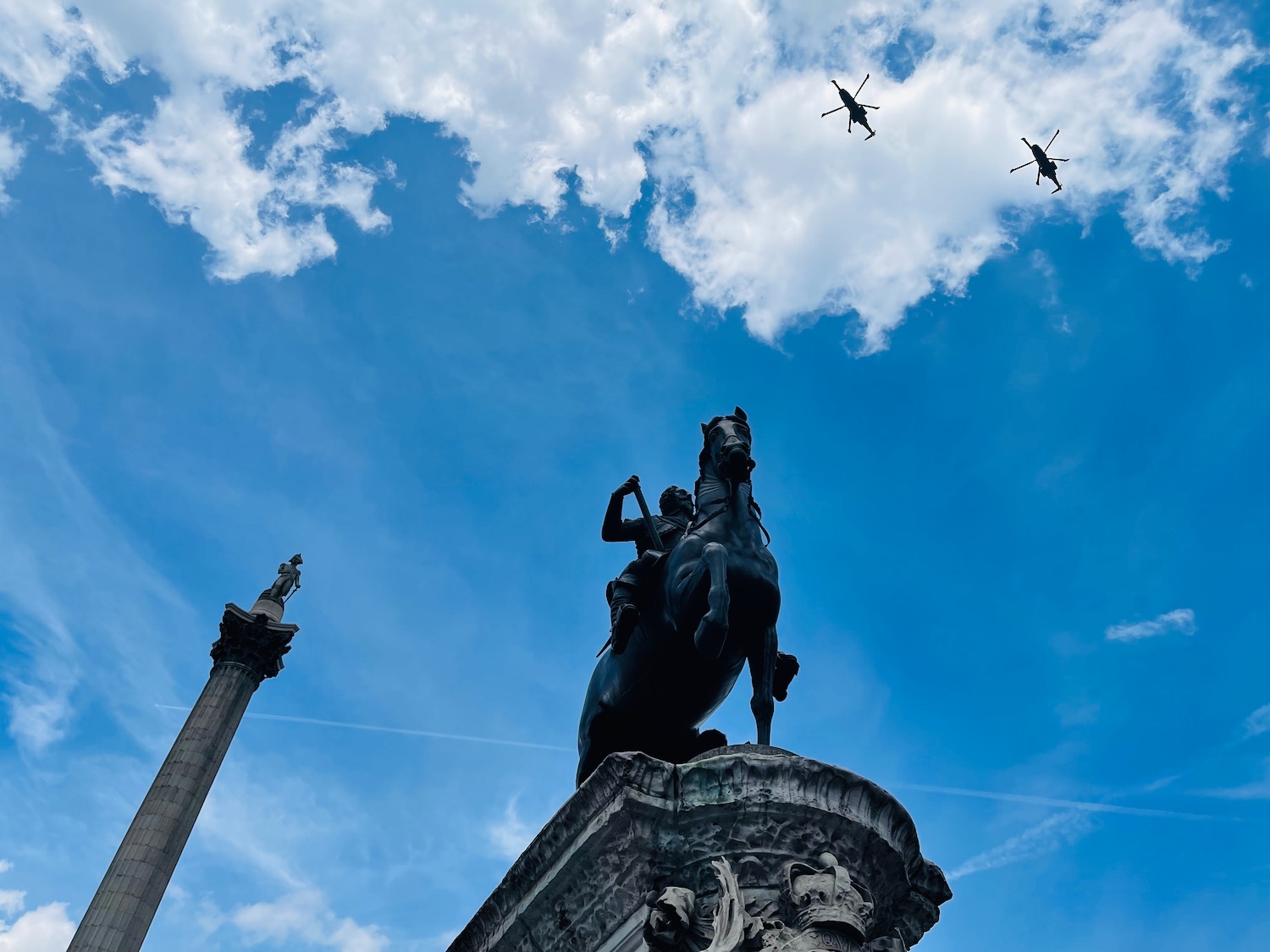 a statue of a man on a horse and two helicopters flying in the sky