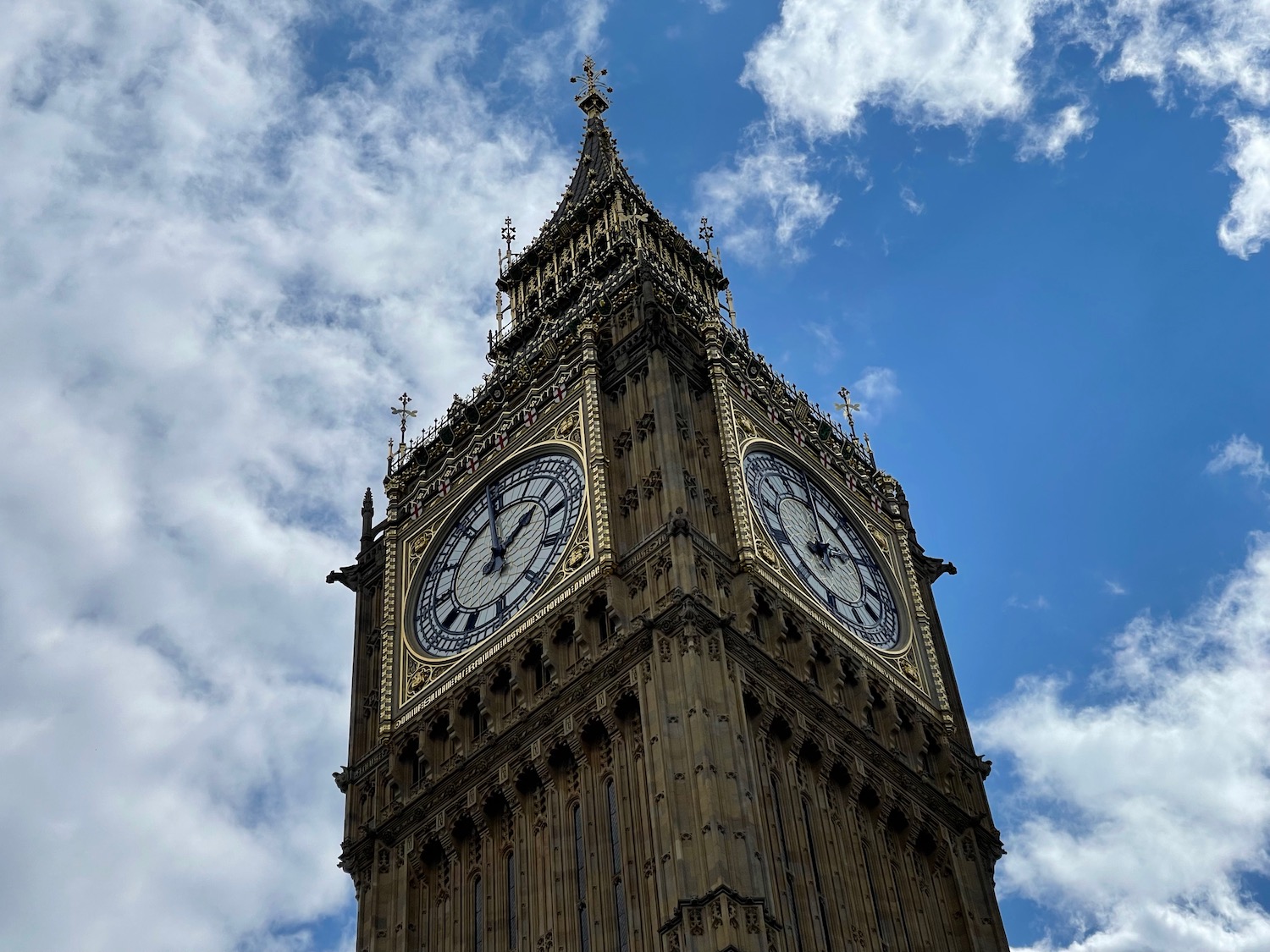 a clock tower with a blue sky and clouds with Big Ben in the background
