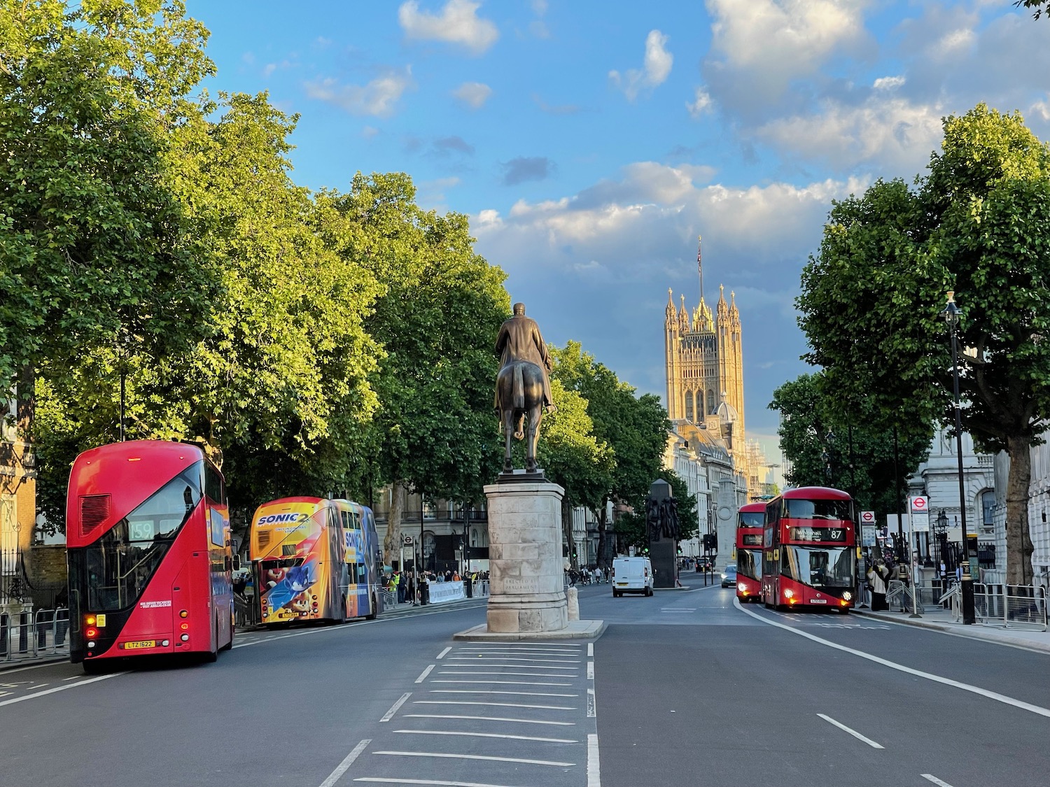 a statue of a horse on a pedestal in a city street with double decker buses