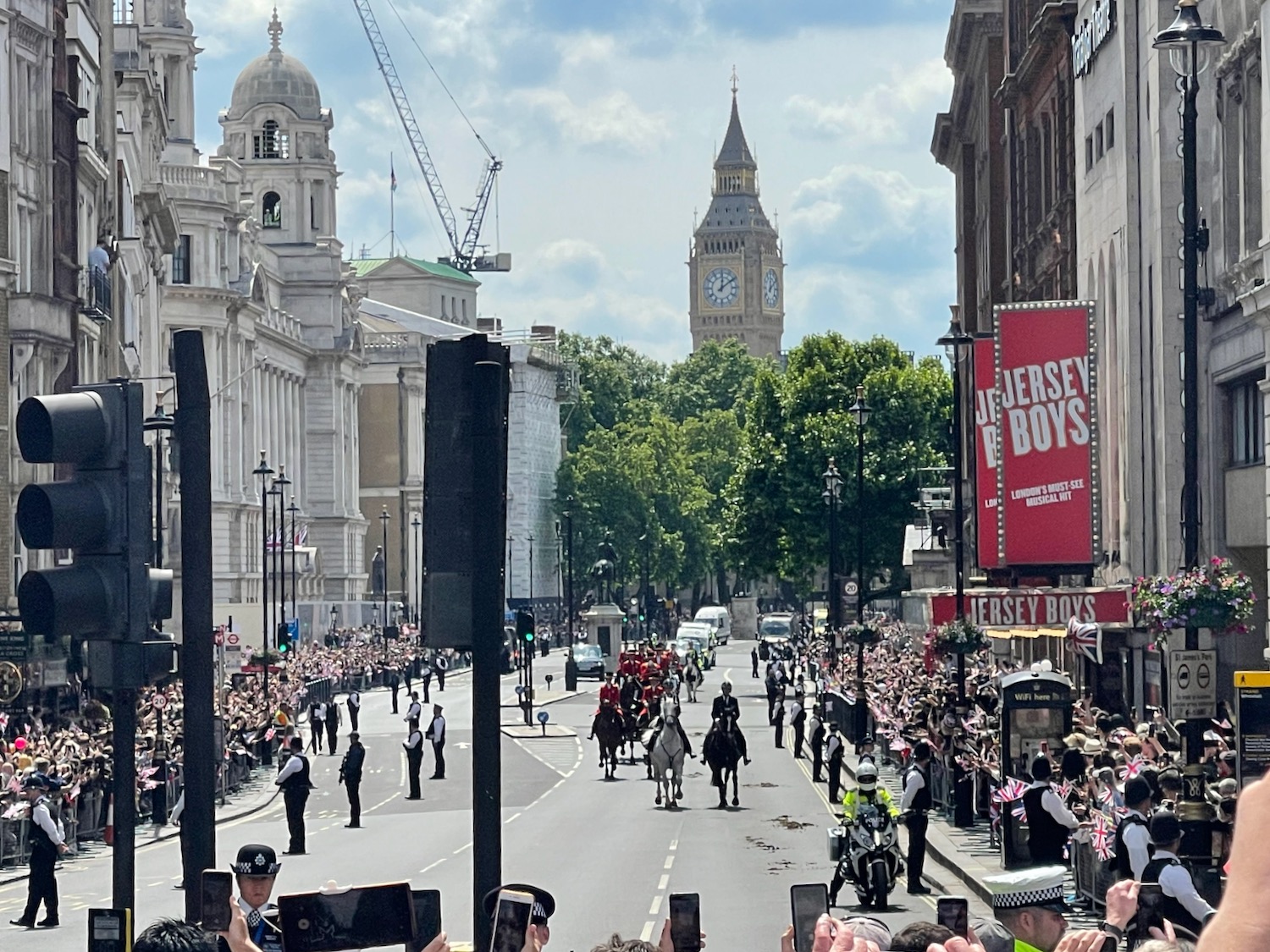 a group of people riding horses in a street with a large crowd of people