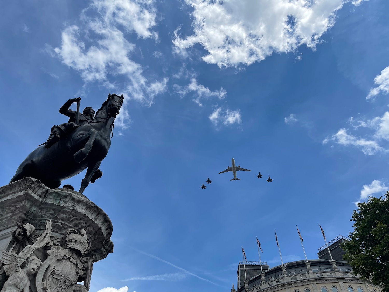 a plane flying over a statue of a horse and a statue of a man