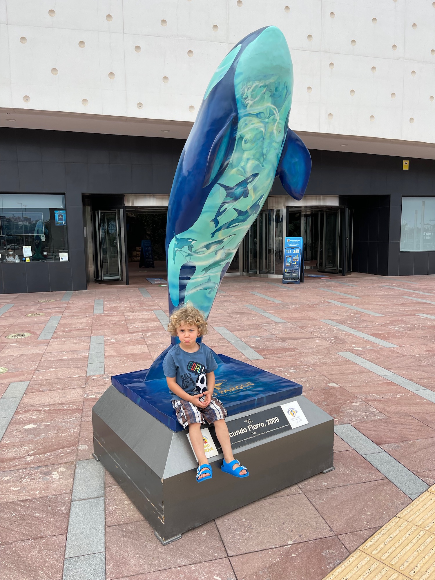 a boy sitting on a statue of a dolphin