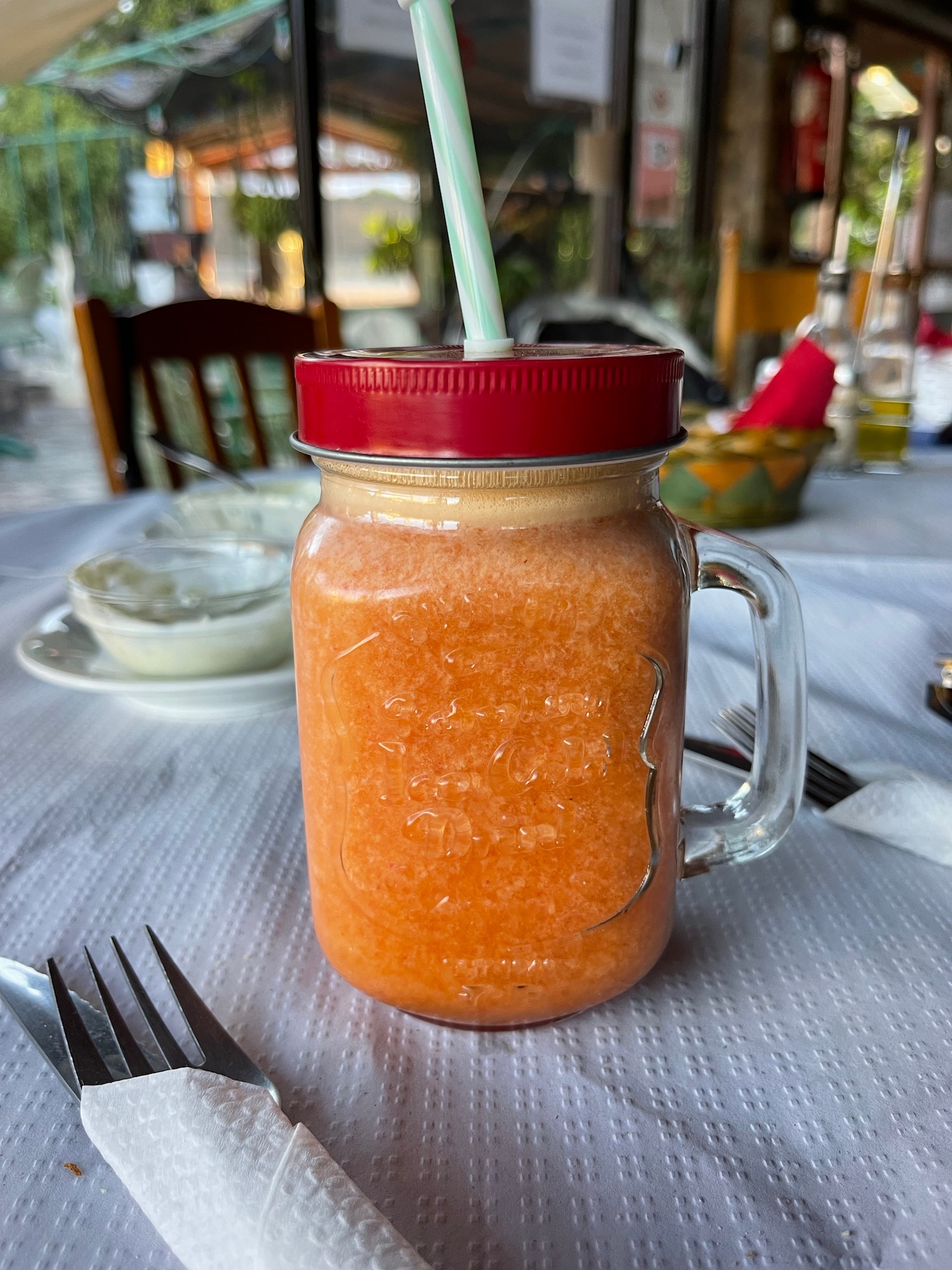 a glass jar with a straw filled with orange liquid