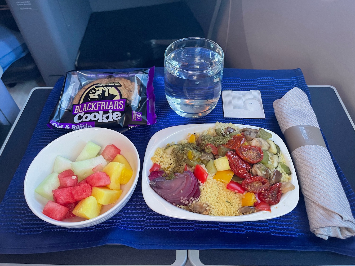 a plate of food and a glass of water on a blue surface