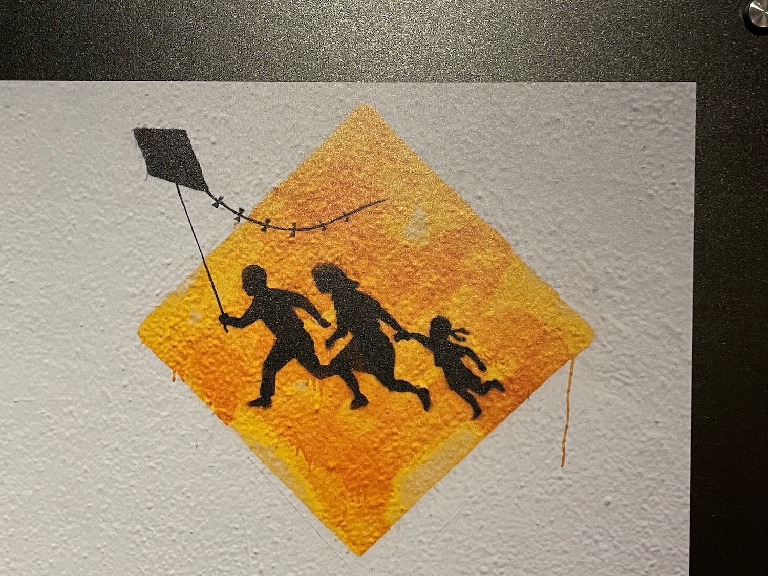 a yellow diamond shaped sign with black silhouettes of people running