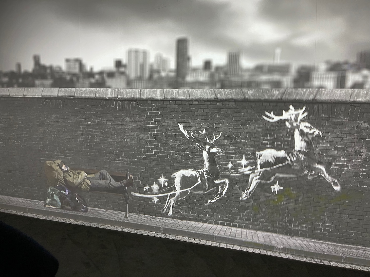 a man on a bench with reindeers running on a wall