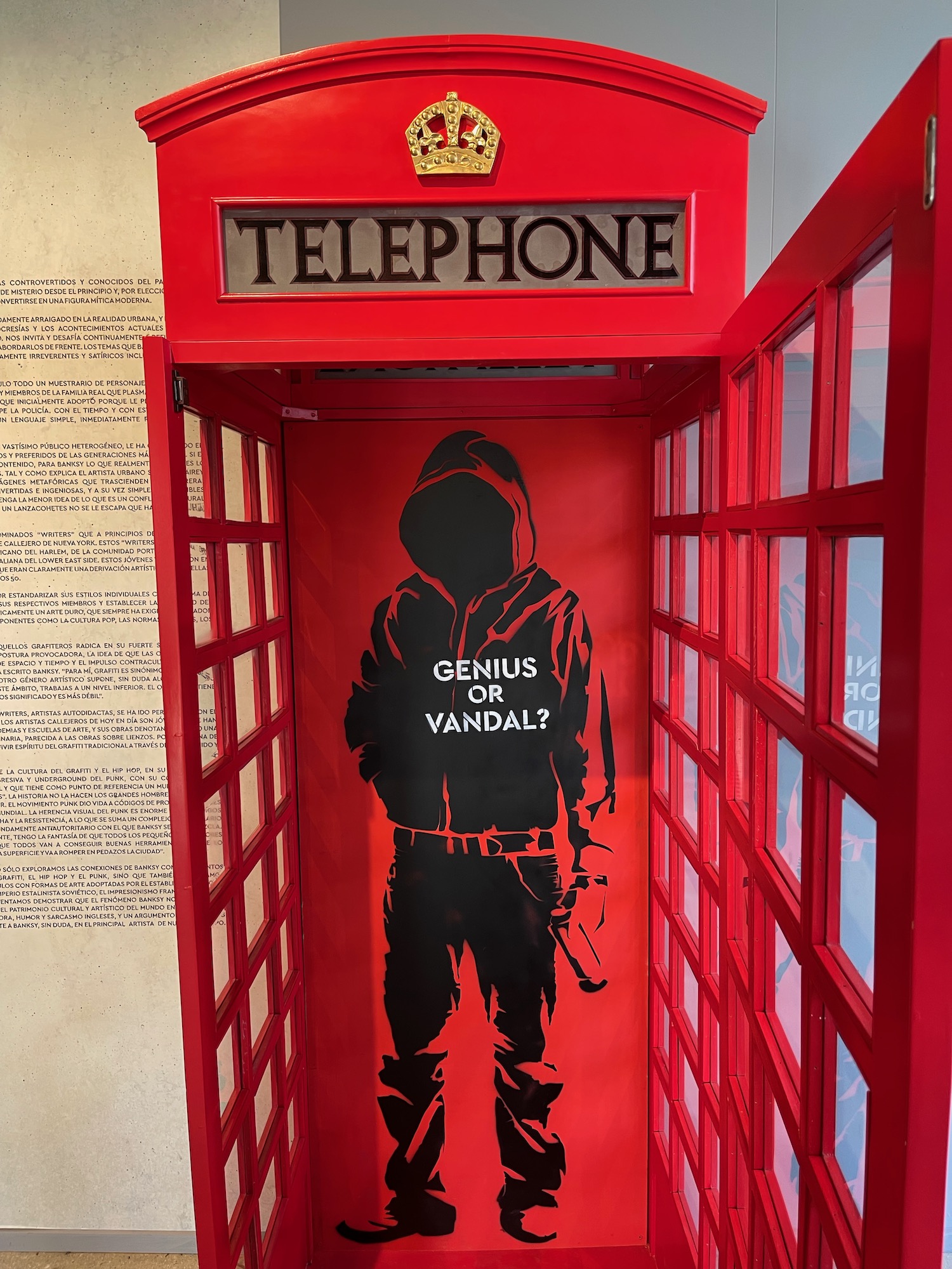 a red telephone booth with a black silhouette of a man in a hoodie