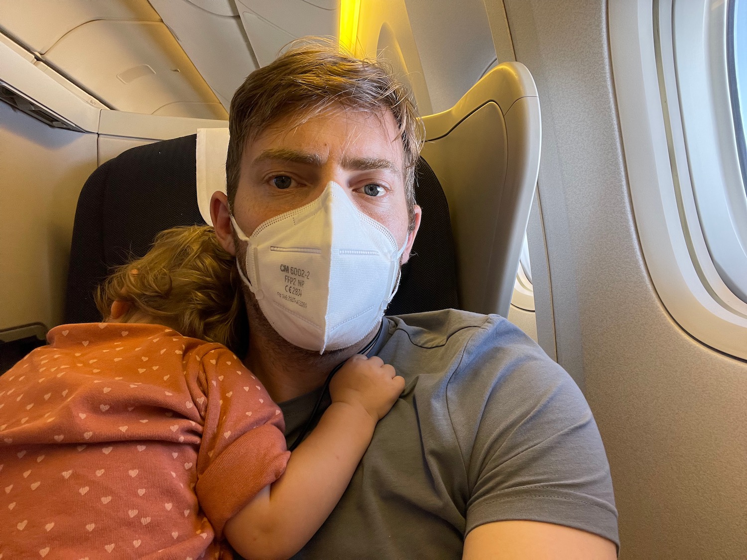 a man with a face mask on his chest and a baby in his arms