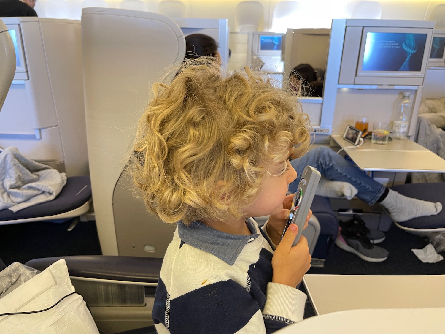 a child sitting in an airplane holding a phone