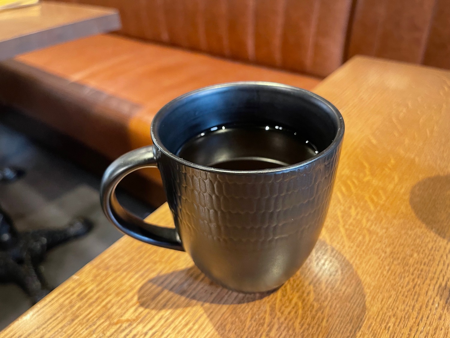 a black mug with liquid on a wooden surface
