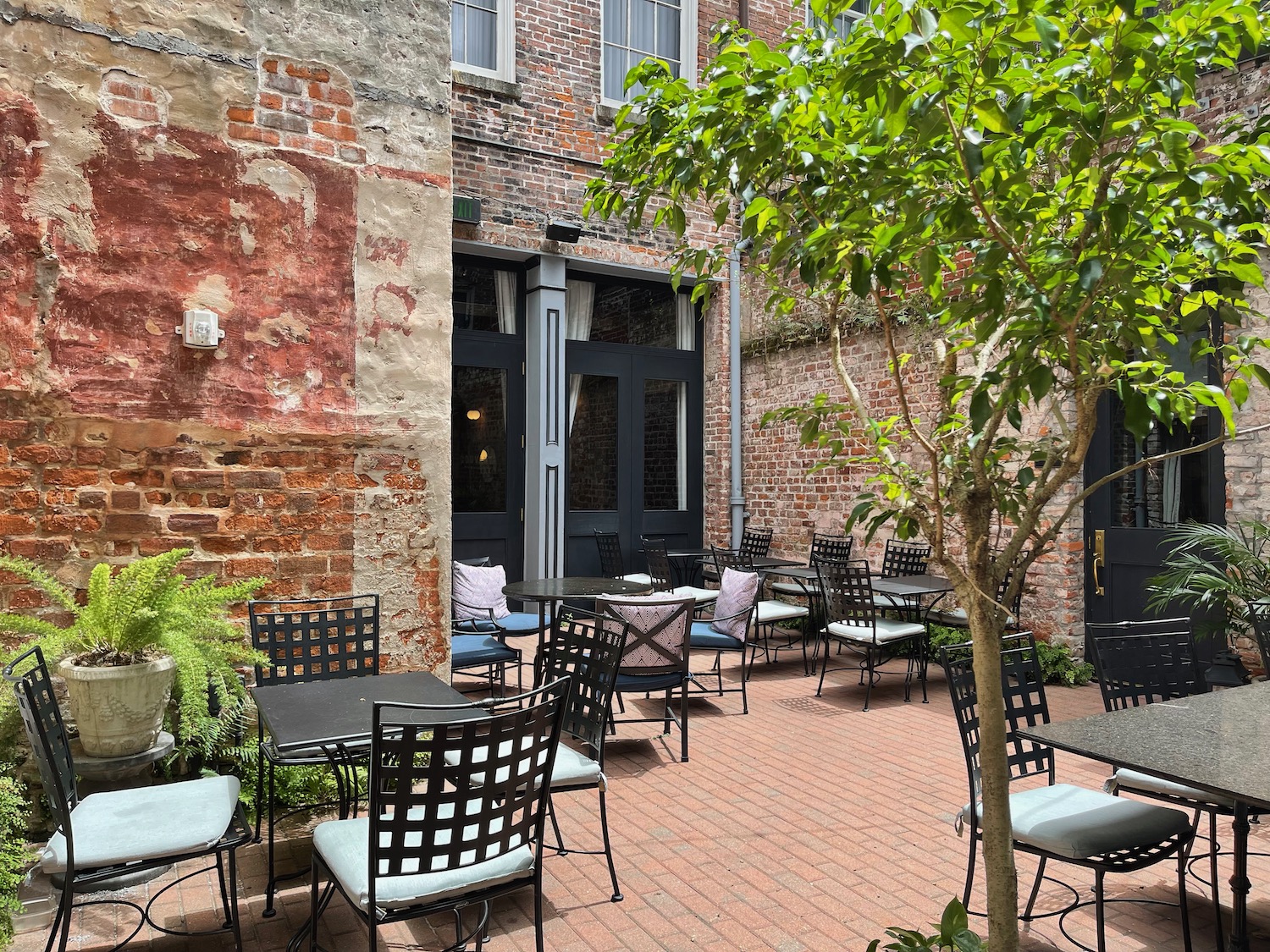a patio with chairs and tables outside of a brick building