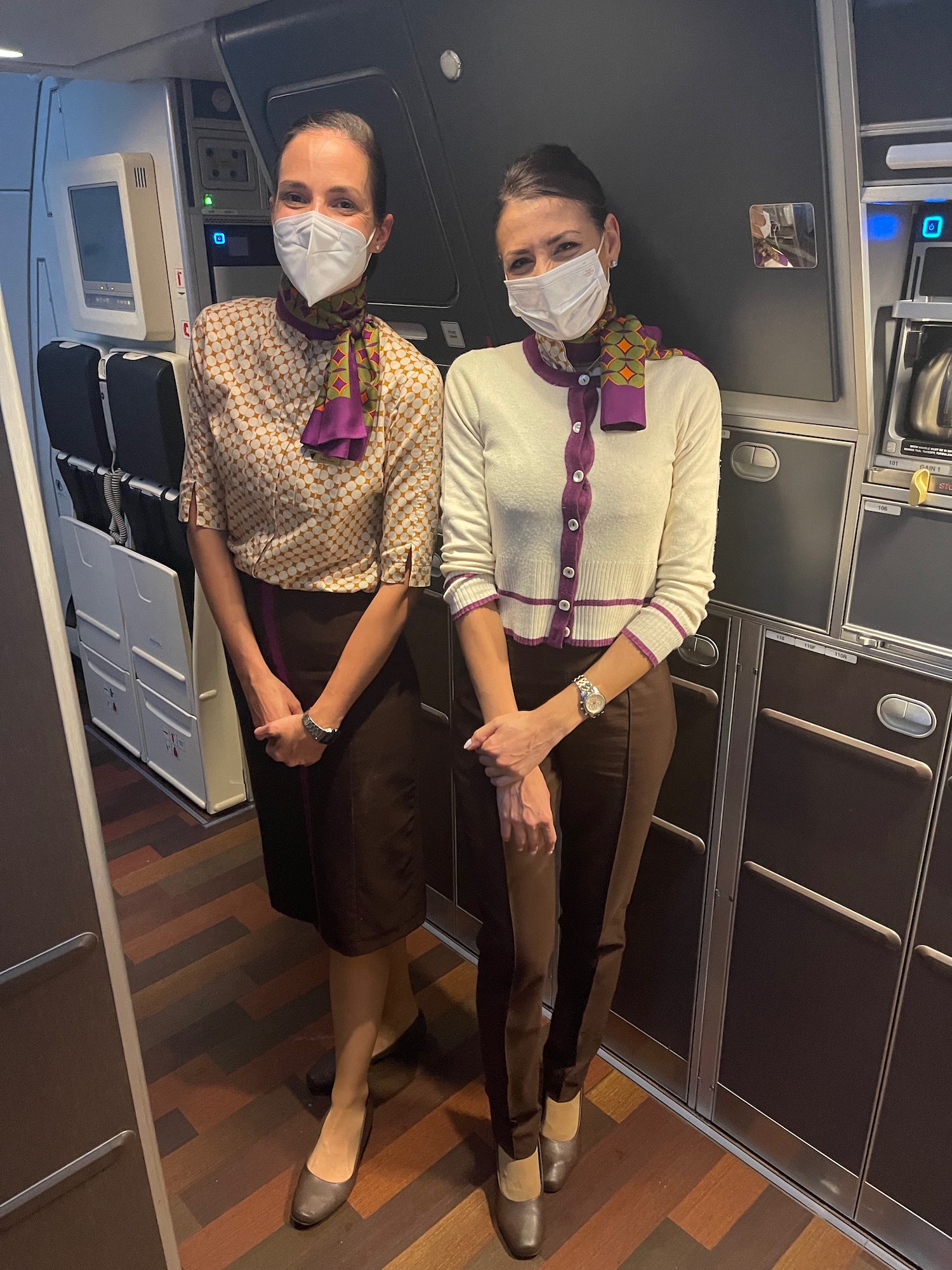 two women wearing masks and standing in a room