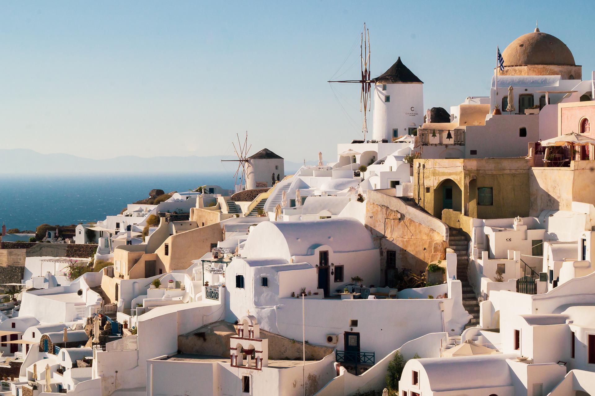 a white buildings with windmills on the hillside