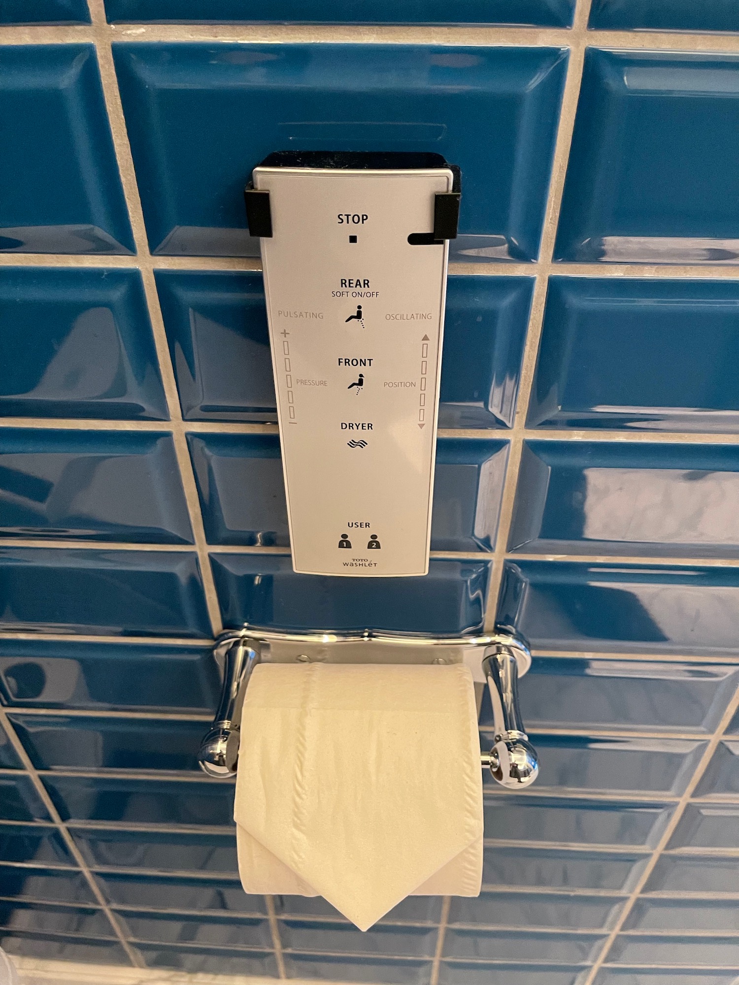 a toilet paper dispenser on a blue tile wall