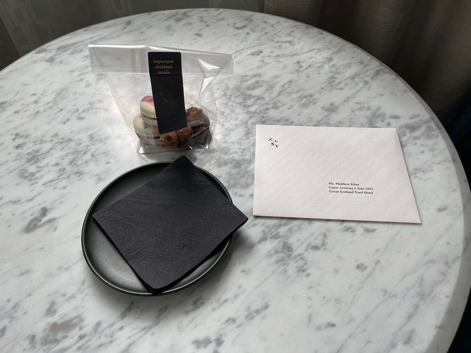 a plate with a black napkin next to a white envelope on a marble table