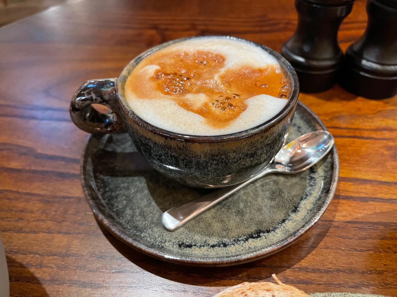 a cup of coffee with foam and a spoon on a saucer