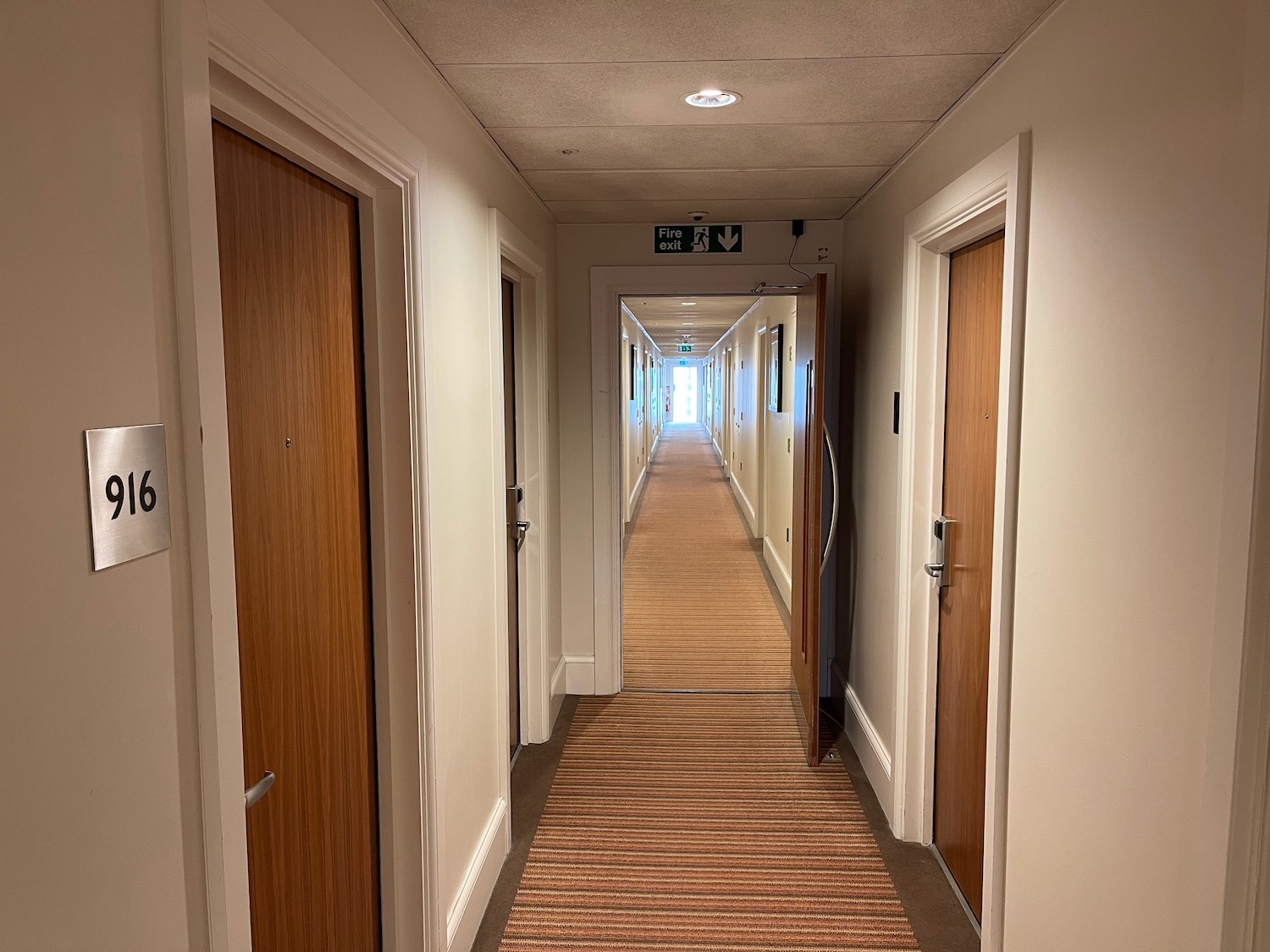 a long hallway with doors and a striped carpet