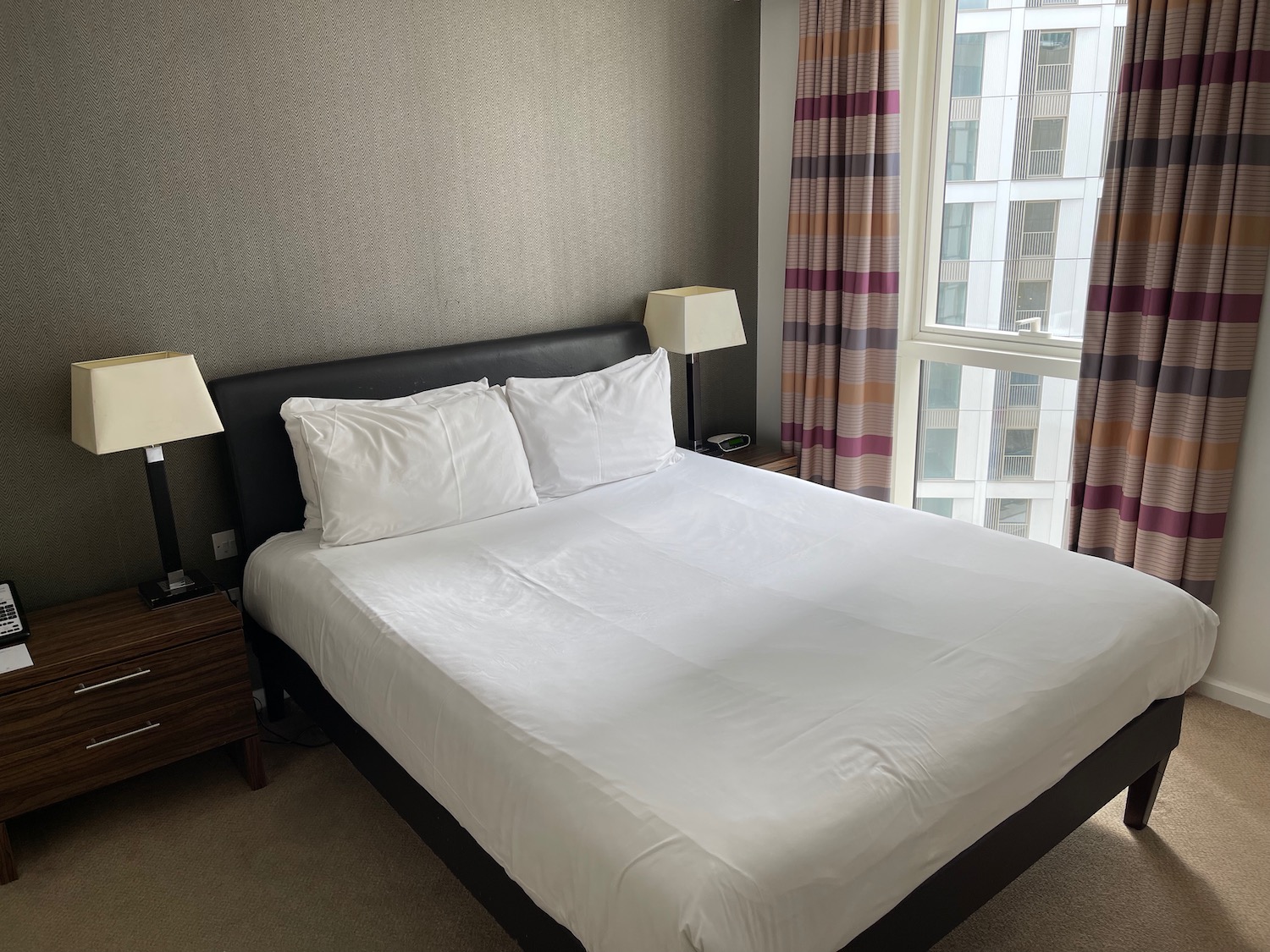 a bed with white sheets and lamps in a room