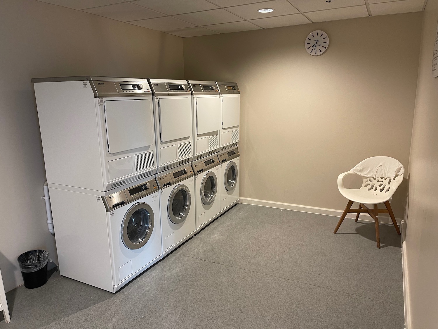 a laundry room with a white chair and a stack of washing machines