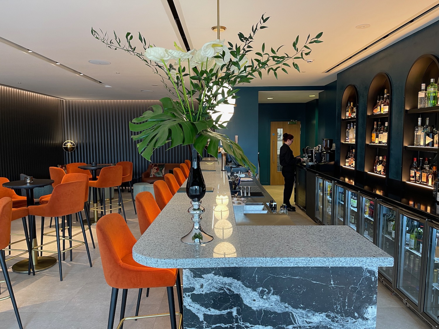 a bar with orange chairs and a vase of flowers