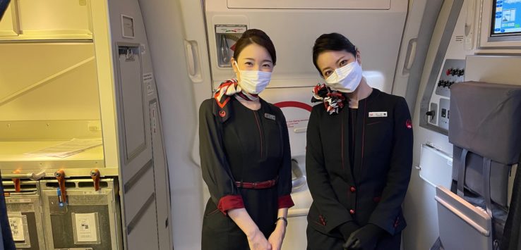 two women wearing face masks in an airplane