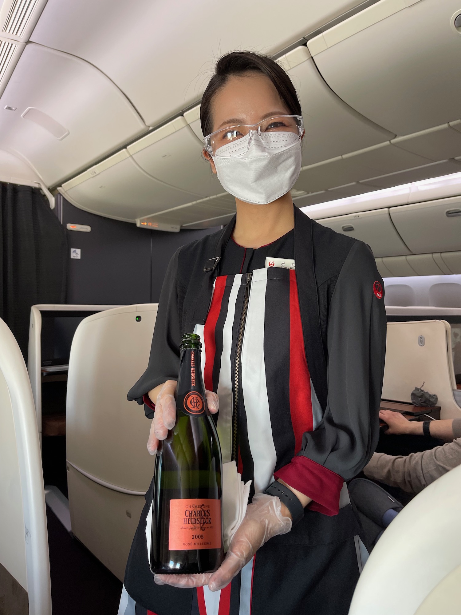 a woman wearing a mask and gloves holding a bottle of champagne