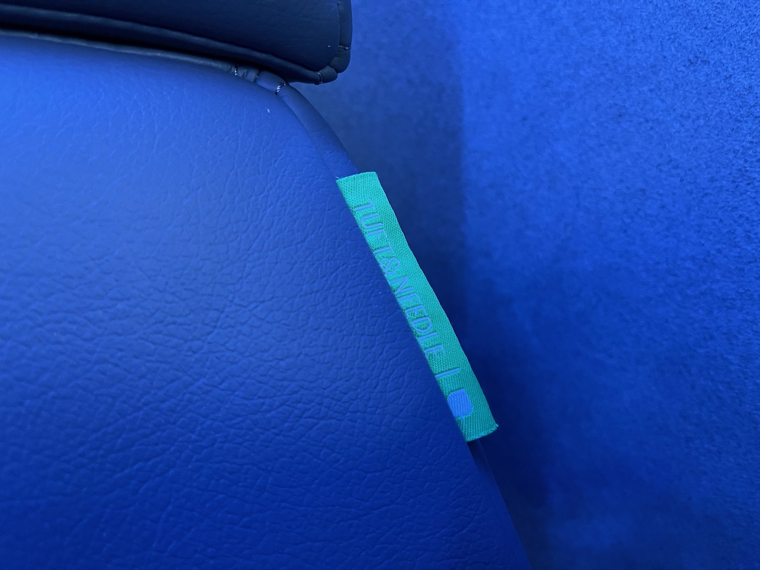 a blue leather seat with a green tag