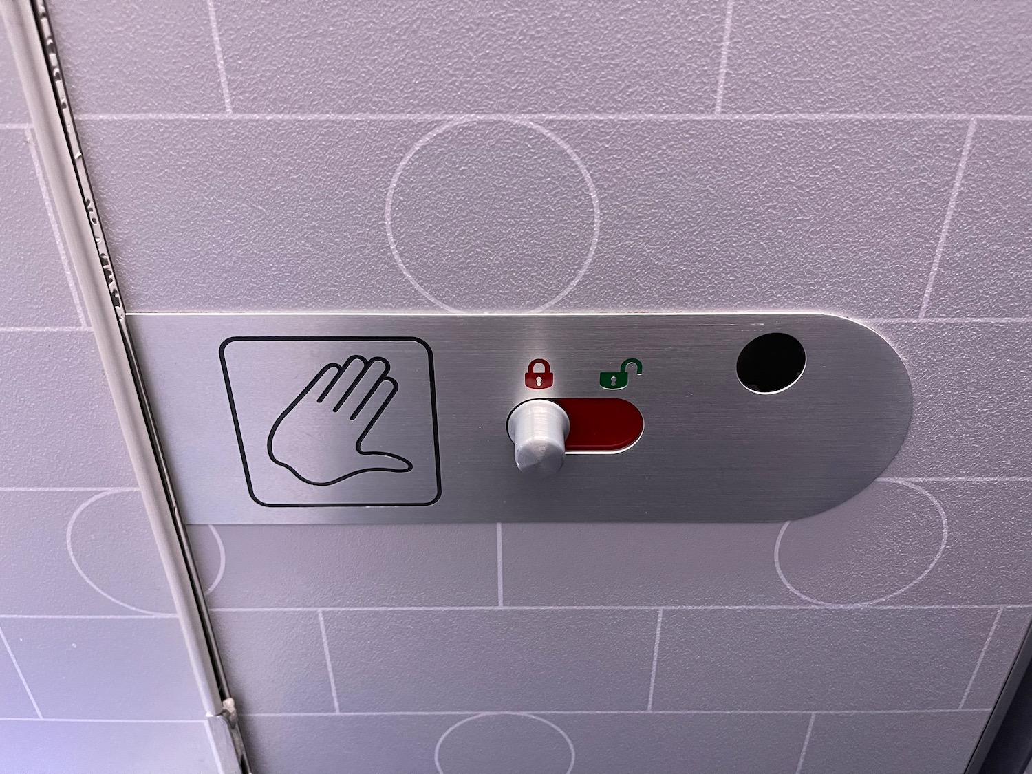 a metal sign with a hand and a button on the wall