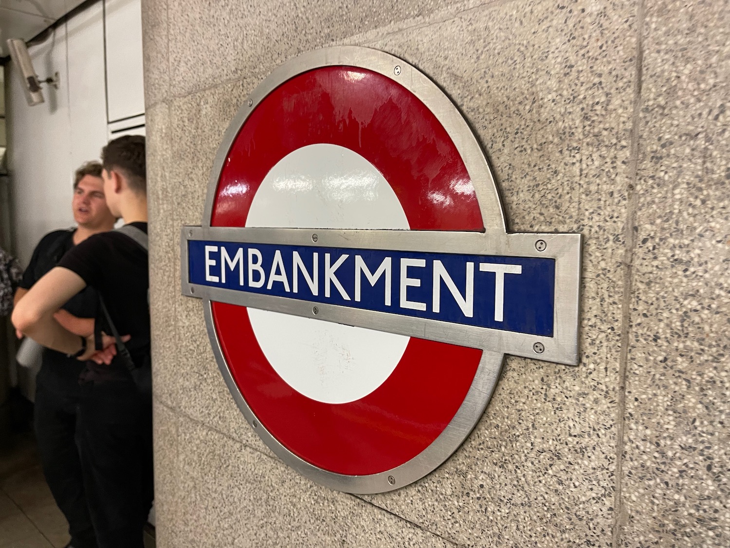 a sign on a wall with London Underground in the background