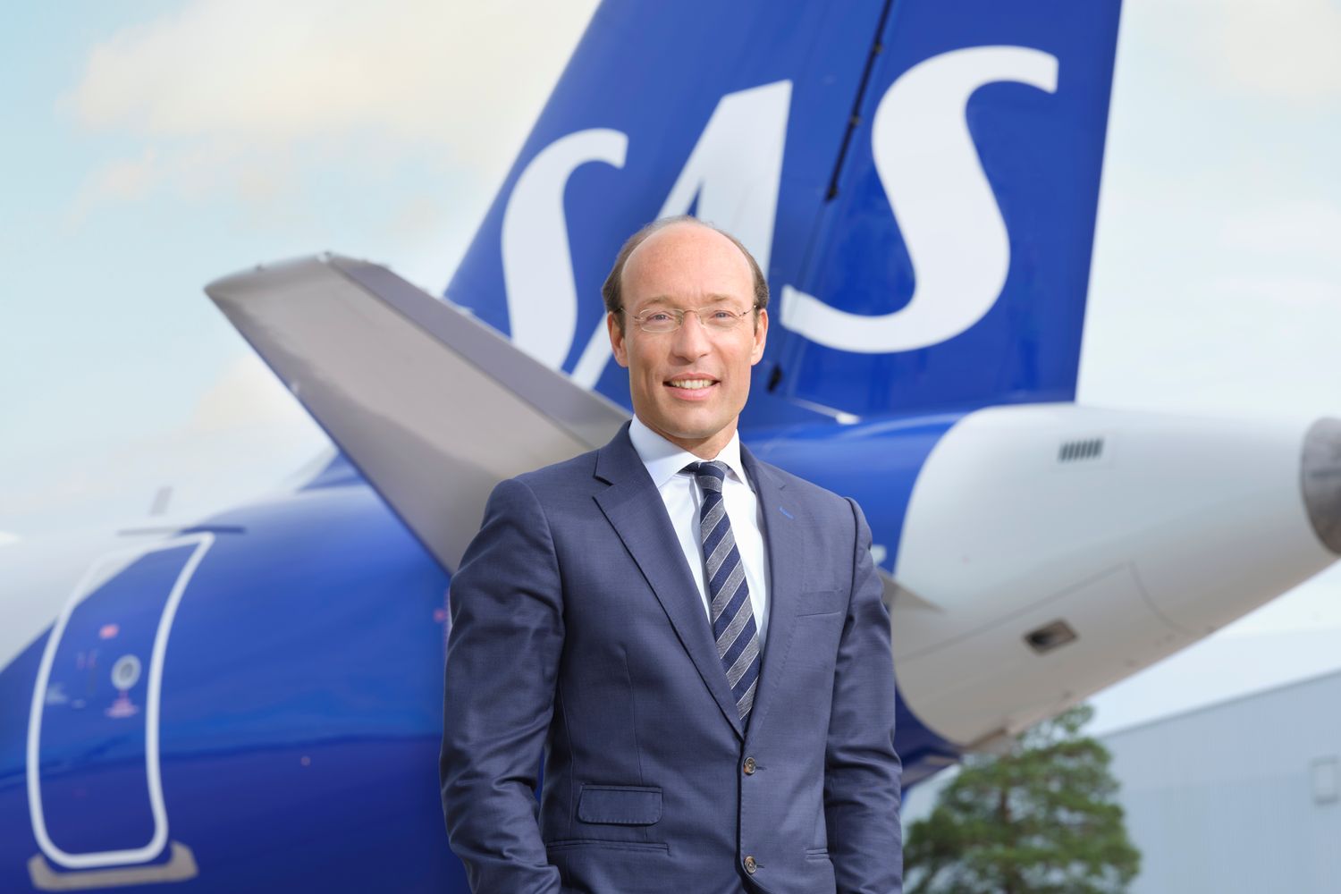 a man in a suit and tie standing in front of a plane