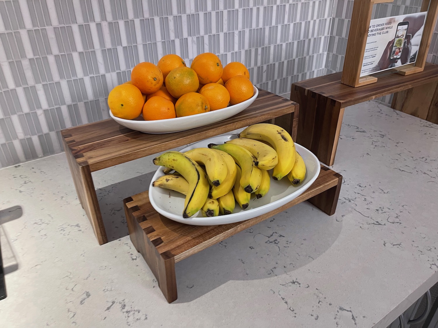 a bowl of bananas and oranges on a wooden shelf