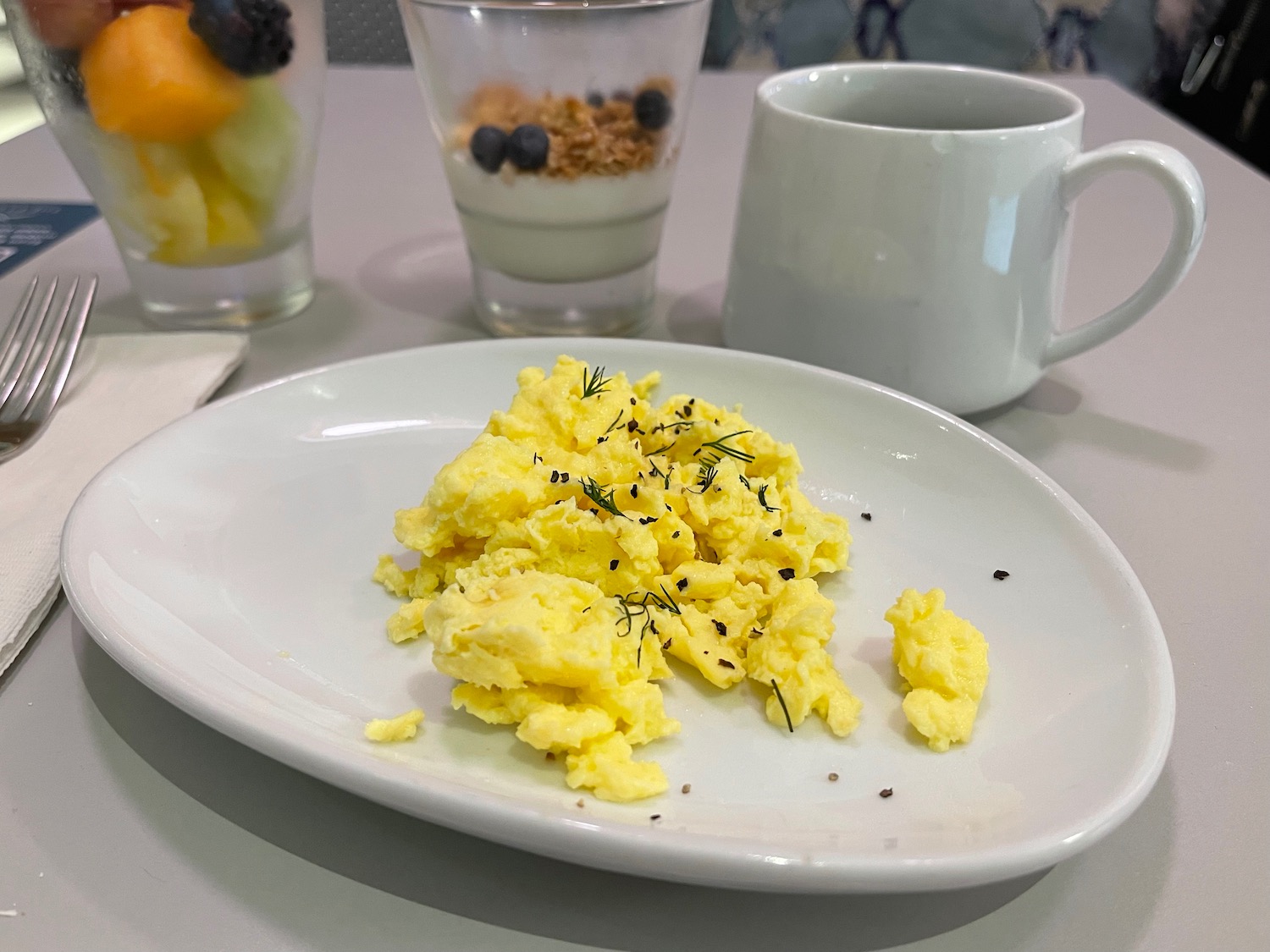 a plate of scrambled eggs and a mug of coffee