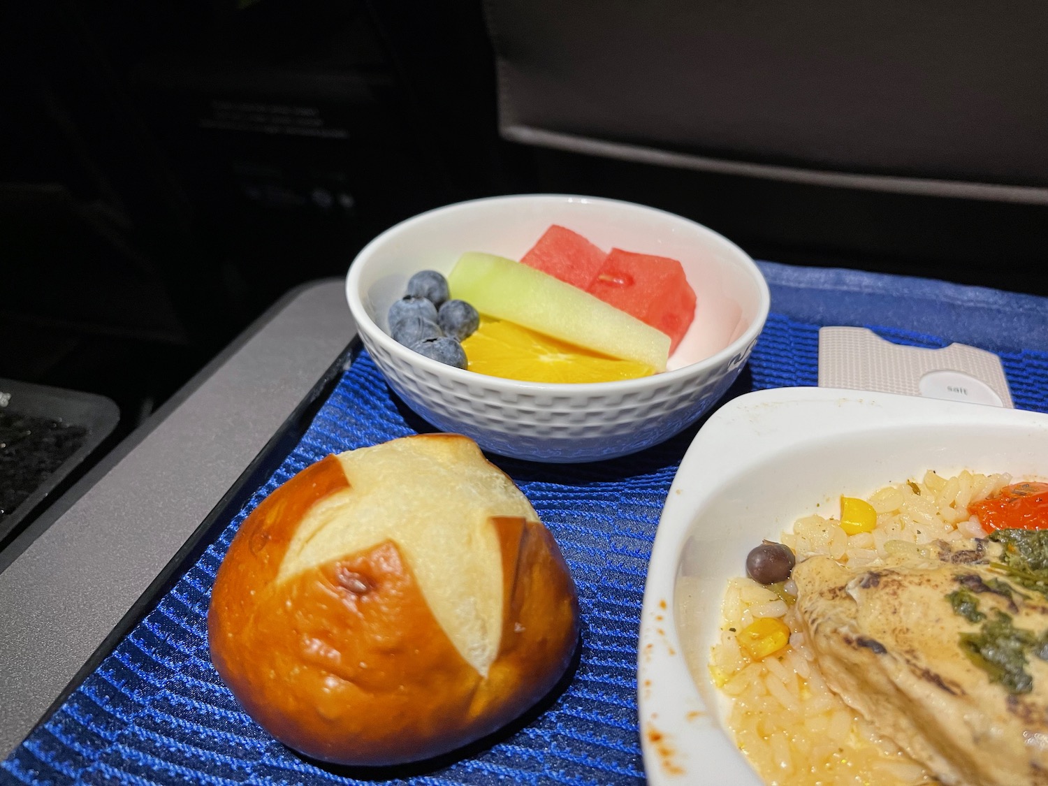 a bowl of fruit and a bun on a tray