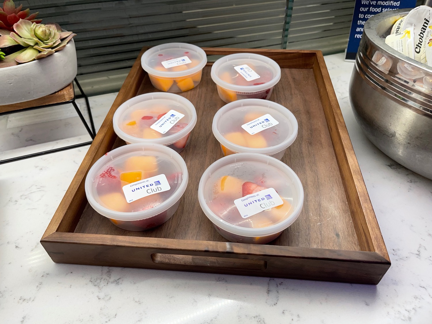 a tray of fruit in plastic cups