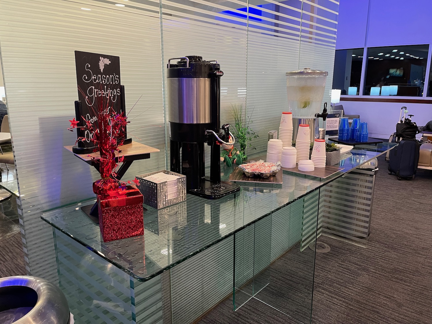 a glass table with a drink dispenser and a container