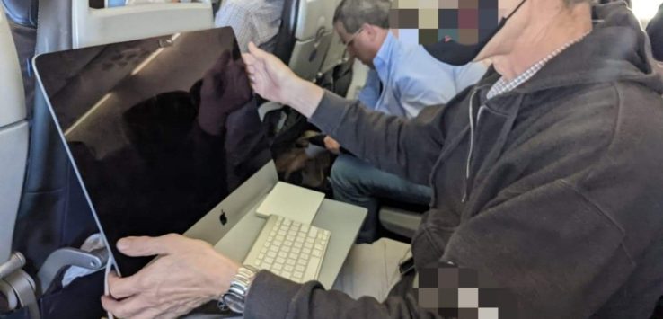 a man sitting in an airplane with a computer