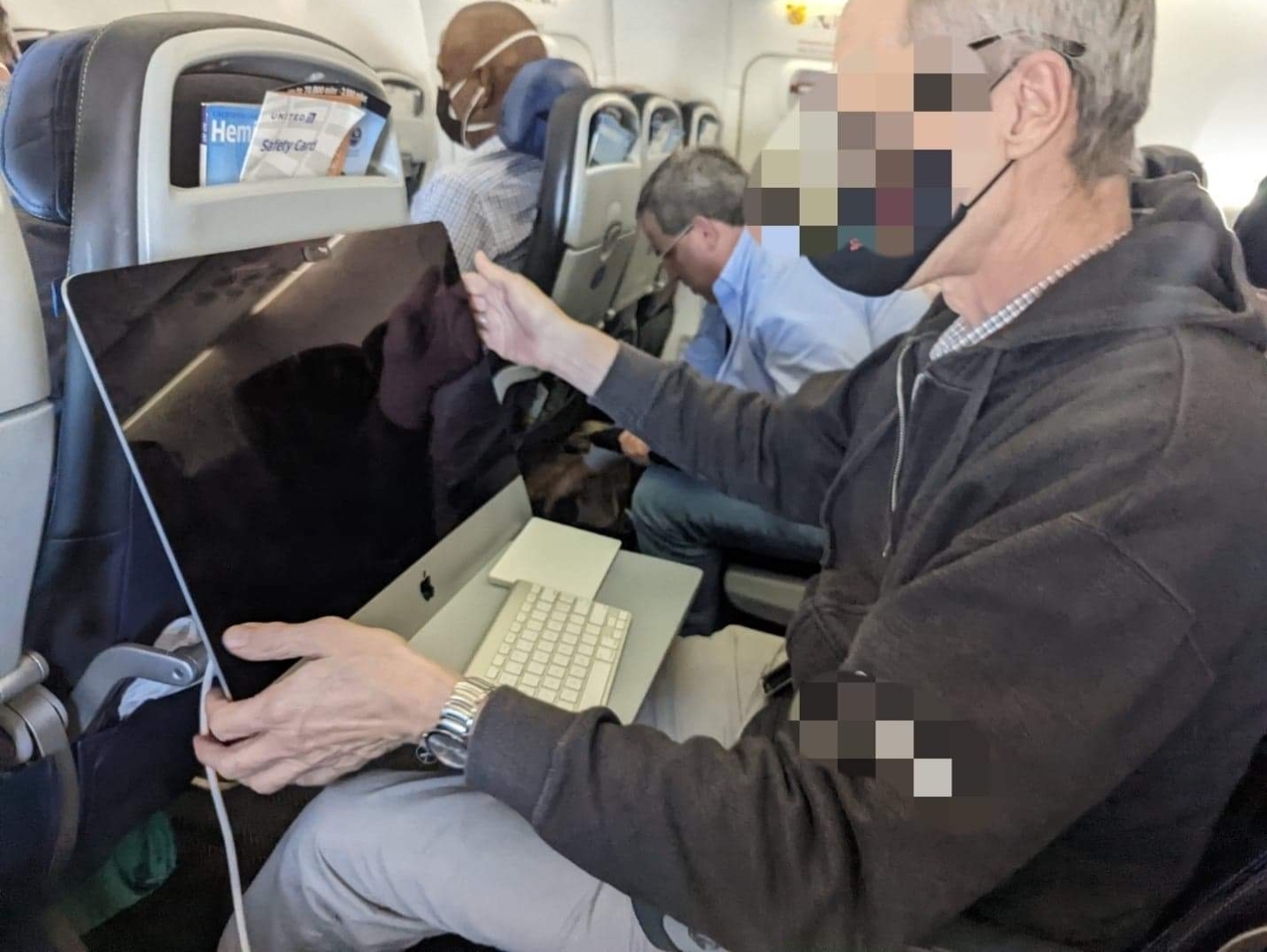 a man sitting in an airplane with a computer