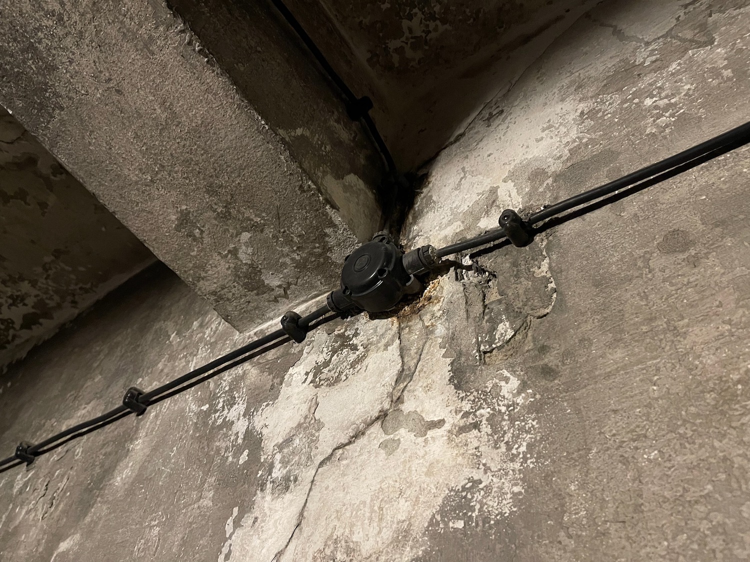 a black electrical wires connected to a concrete wall