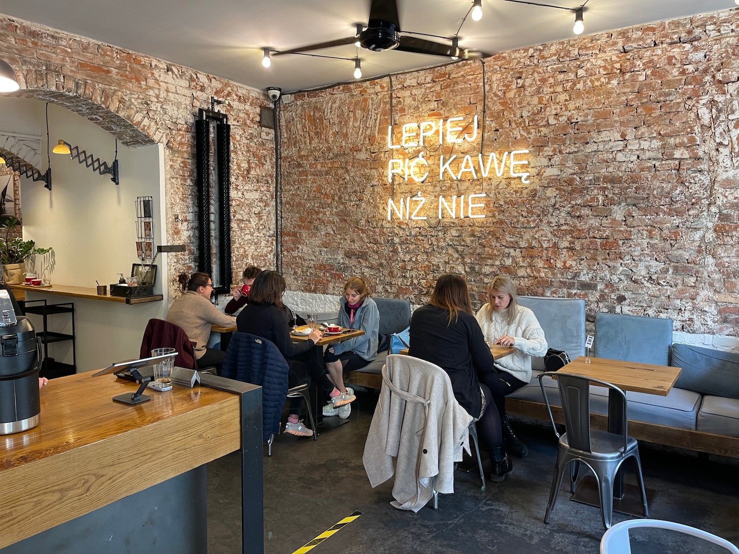 a group of people sitting at tables in a room with a brick wall