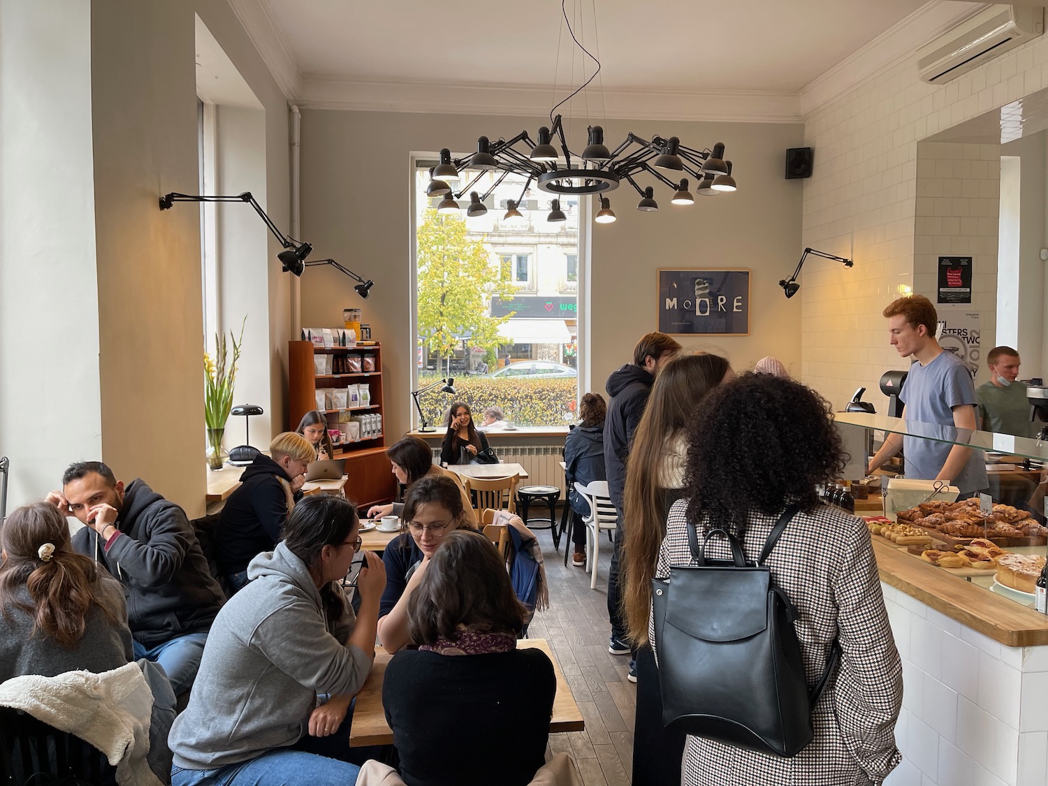 a group of people sitting at tables in a room with a chandelier