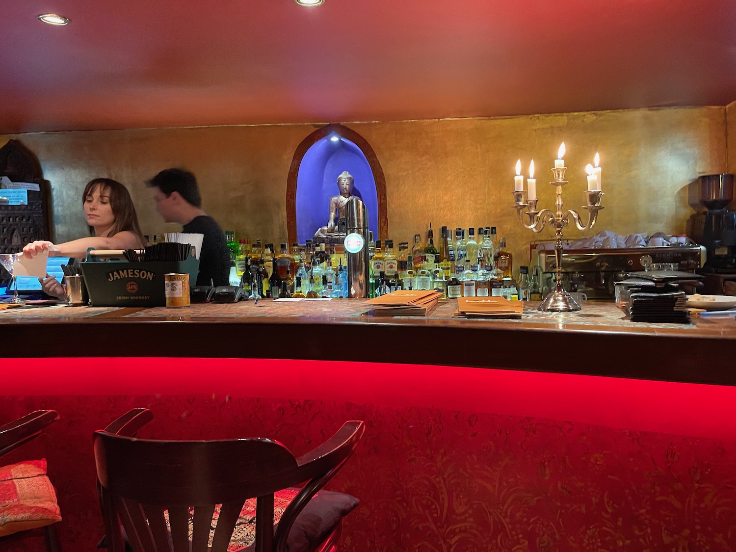 a bar with a statue of a buddha behind it