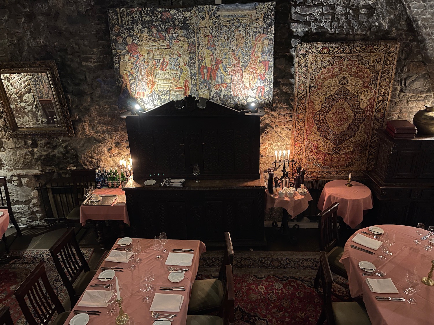 a room with a stone wall and a table with pink tablecloths