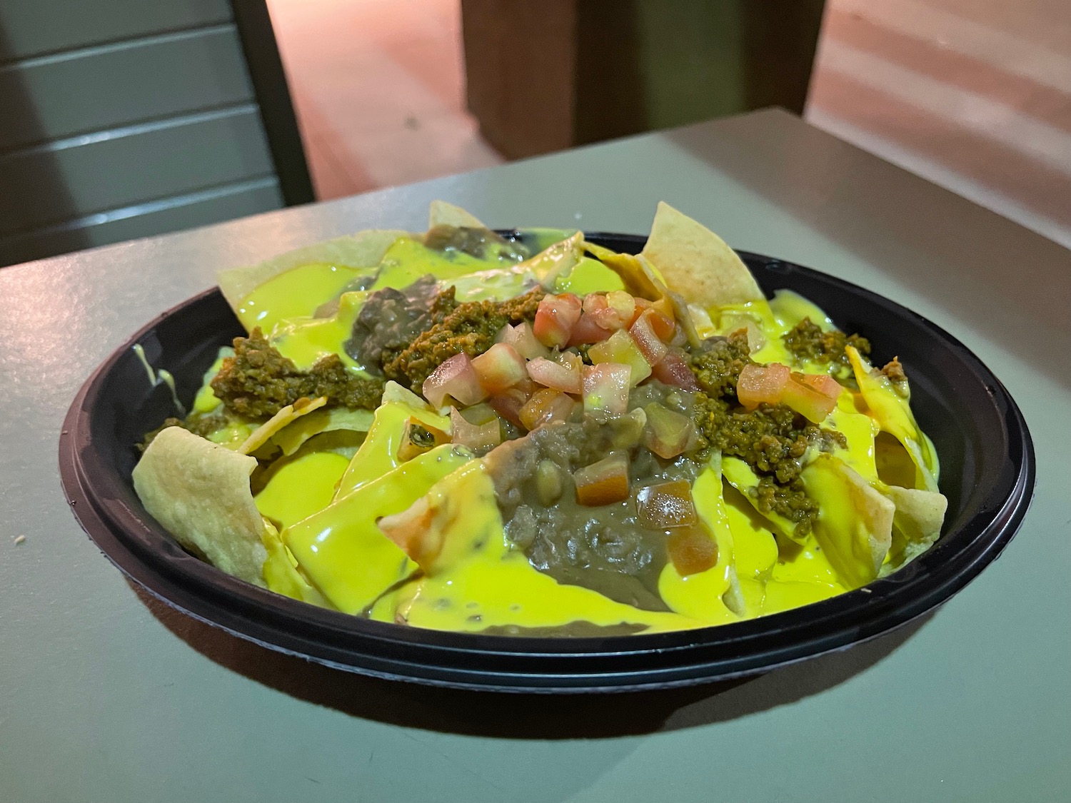 a plate of nachos with cheese sauce and salsa